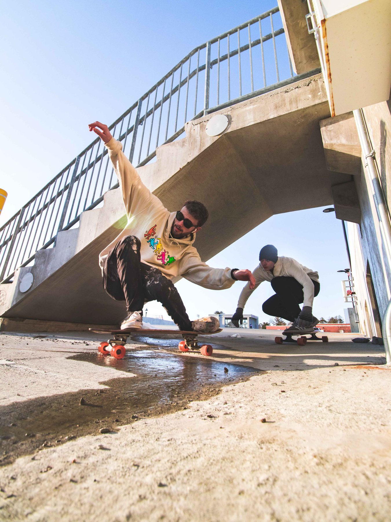 Two longboarders carving under an overpass